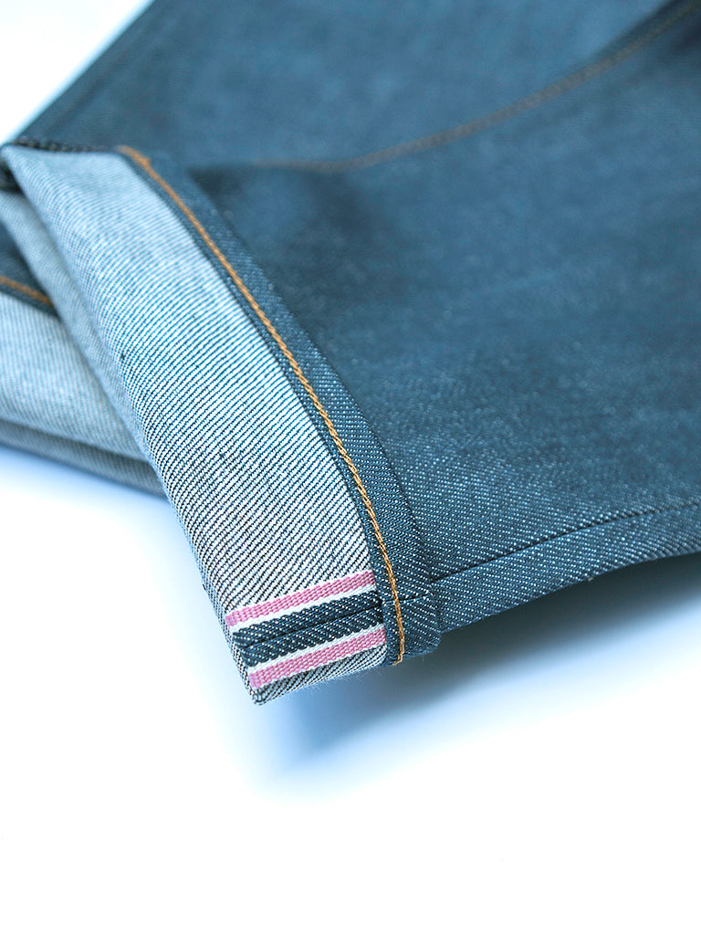 Close-up of folded dark gray denim fabric showing the inner hem with contrast stitching and striped inner lining on a white background.