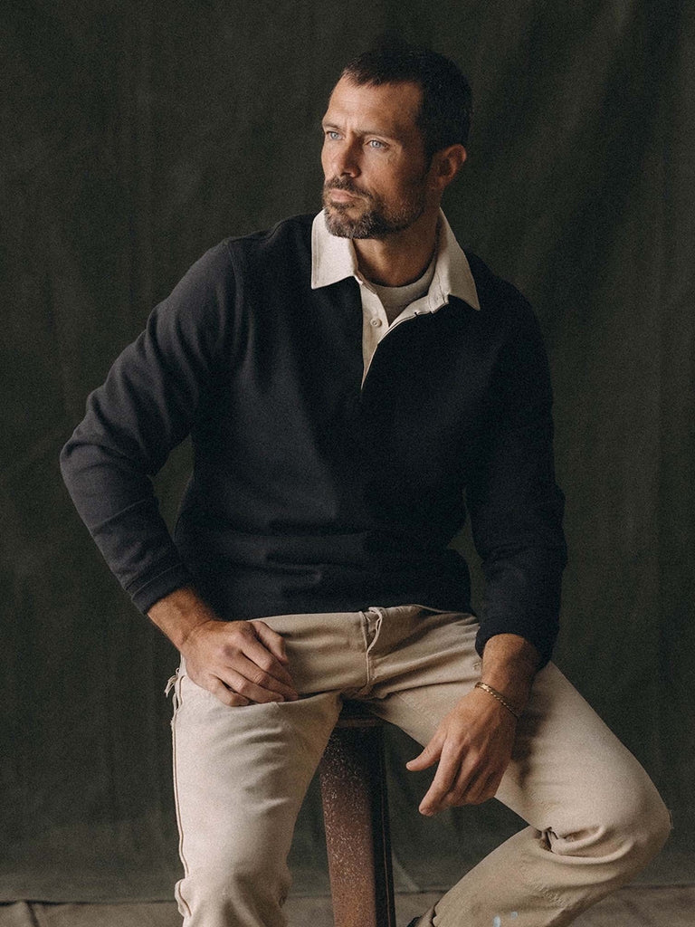 A man wearing a black long-sleeve polo with white collar and khaki pants