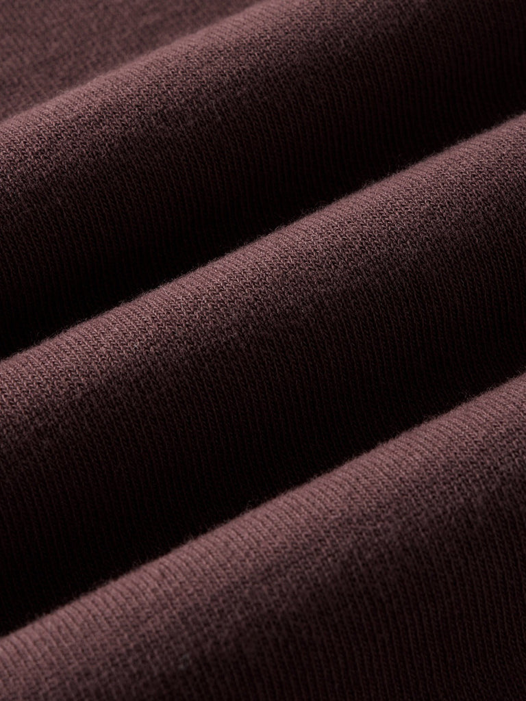 A close-up of draped ribbed knit fabric in a deep dark burgundy color