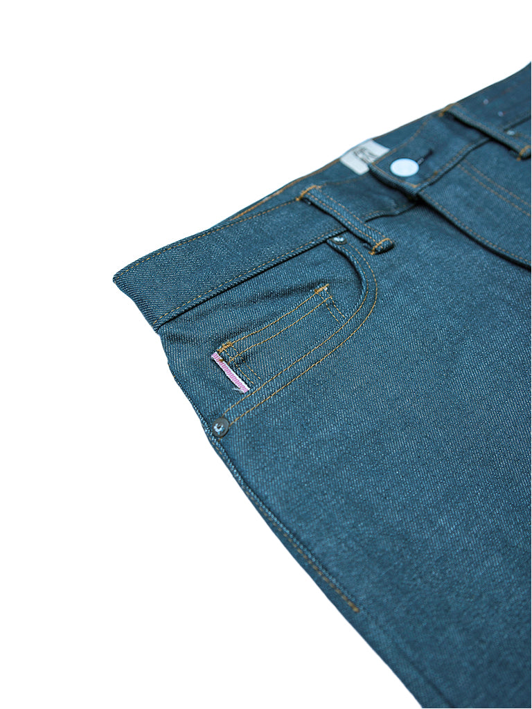 Close-up of the waistband and right pocket area of dark indigo denim jeans on a white background.