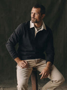 A man wearing a black long-sleeve polo with white collar and khaki pants