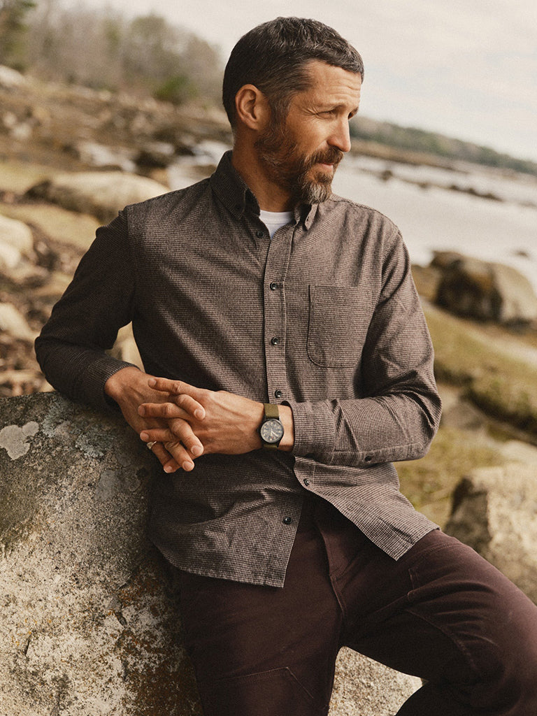 A man wearing a brown houndstooth button-down shirt and brown pants