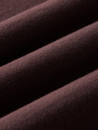 A close-up of draped ribbed knit fabric in a deep dark burgundy color