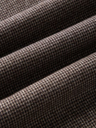 A close-up of fabric with a houndstooth pattern in brown and black.